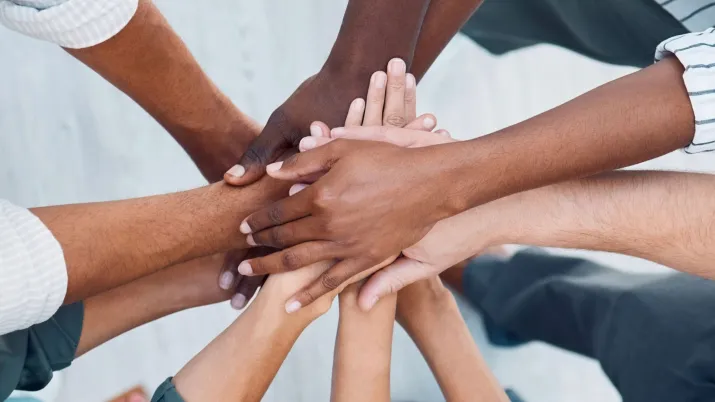 Groupe de personnes, mains les unes sur les autres, prise vue d'en haut. 